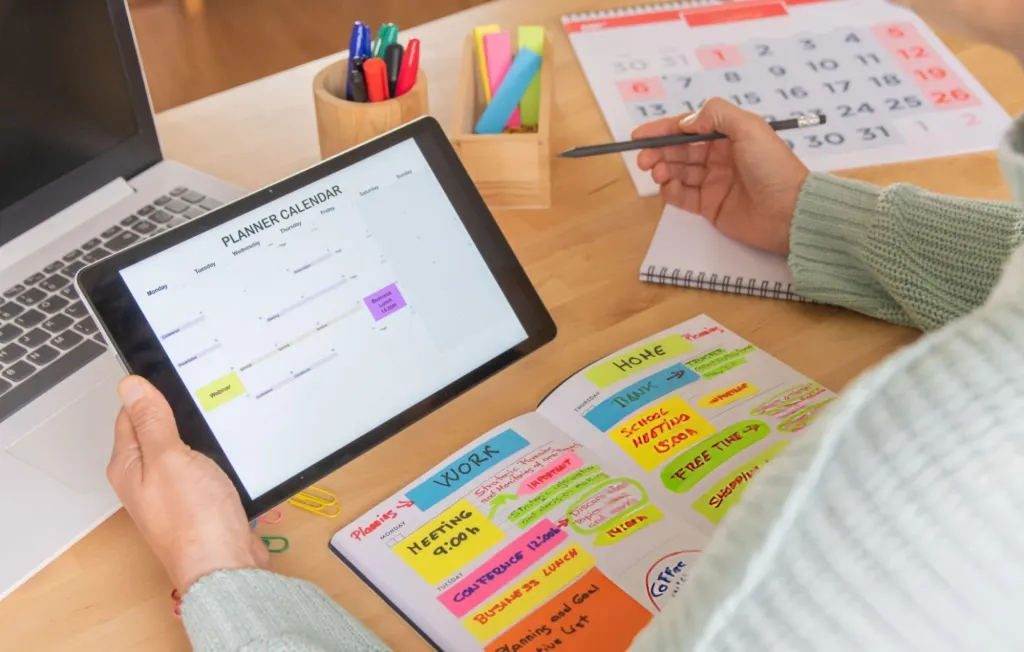 Small business owner planning a month of social media content with a tablet calendar and colour-coded planner